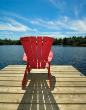 red muskoka chair on lake dock